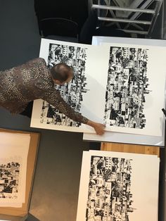 a man working on an art piece in front of two large paintings with black and white designs