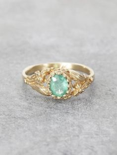 A lush Golden Garden of delicately detailed wildflowers and gracefully winding leaves, reveals a precious, crowned Emerald jewel set in Solid 14K Gold. This would make an exceptional & unique Engagement Ring. Additional gems are also available by request. This extra fine beautiful quality Colombian Emerald measures 6x5.5mm and is approx. .65ct. Ring measures 7.5mm at the front, tapering to a 1.8 mm band. Handcrafted with Love by Elise Perelman in NYC.  We recommend double-checking your ring size Nature-inspired Oval Emerald Ring, Nature-inspired Yellow Gold Gemstone Rings, Elegant May Birthstone Flower Ring With Gemstone, Nature-inspired Yellow Gold Jewelry With Rose Cut Diamonds, Wedding Emerald Ring With Intricate Design, Fine Jewelry Emerald Ring With Intricate Design For Wedding, Fine Jewelry Yellow Gold Emerald Ring With Intricate Design, Nature-inspired 14k Gold Oval Jewelry, Nature-inspired Oval 14k Gold Jewelry