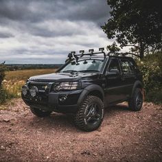 a black truck parked on top of a dirt road