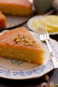 a piece of cake on a plate with a fork next to it and some lemons