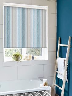 a bathroom with blue walls and a white bathtub next to a ladder in front of the window