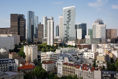 there are many tall buildings in the city with red roofs and green trees on both sides