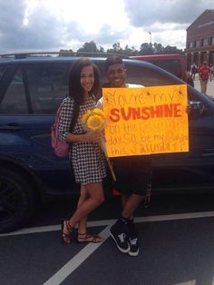 two people standing in front of a car holding a sign that says you're my sunshine