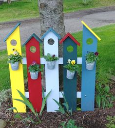 a group of colorful birdhouses sitting on top of a patch of dirt next to a tree