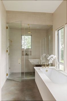 a bathroom with a walk in shower next to a bathtub and sink under a window