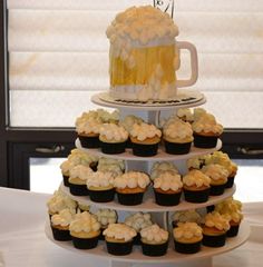 a tiered cake with cupcakes and a beer on top