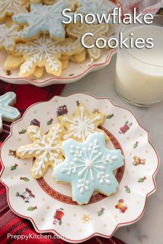 two plates with snowflake cookies on them next to a glass of milk