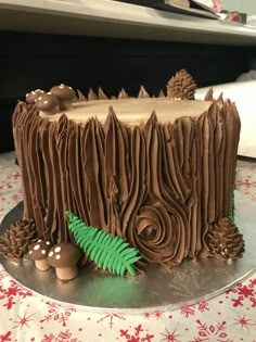 a cake with chocolate frosting and decorations on a silver platter next to a christmas tree stump