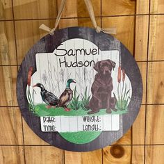 a wooden sign hanging on the side of a building with two dogs and ducks in front of it