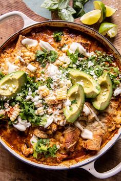 a large pot filled with mexican food and topped with avocado slices on top