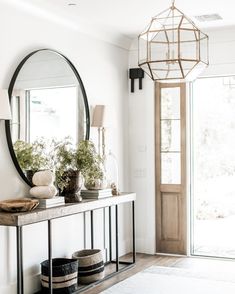 a hallway with a mirror, vases and baskets on the table in front of it