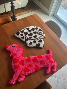 two knitted dogs sitting on top of a wooden table next to eachother