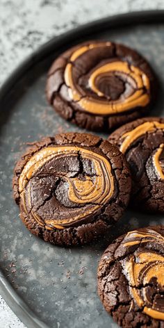 chocolate cookies with orange swirled frosting are on a black plate, ready to be eaten