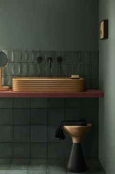 a bathroom with green walls and black tiles on the wall, along with a wooden sink