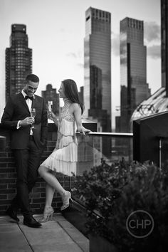 a man in a tuxedo standing next to a woman on a roof top