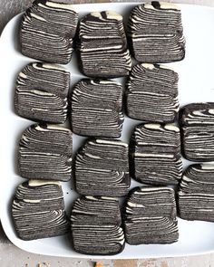 a white plate topped with cut up cookies covered in frosting and brownies on top of a table