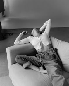 a woman laying on top of a couch with her feet up and arms behind her head