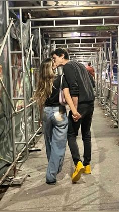 a man and woman kissing on the sidewalk in front of some metal scaffolding