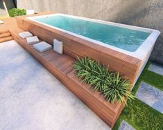 an outdoor swimming pool surrounded by grass and wooden decking, with planters on the side