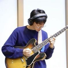 a man with headphones playing an electric guitar