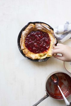 a person holding a piece of bread over a skillet filled with food