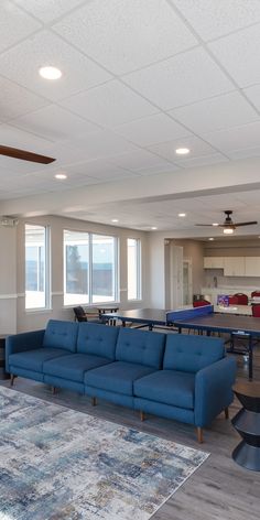 a living room filled with blue couches and tables in front of large open windows