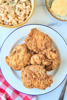 fried chicken and macaroni salad on a plate next to a bowl of macaroni salad