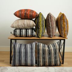 four pillows stacked on top of each other in front of a white wall and wooden floor