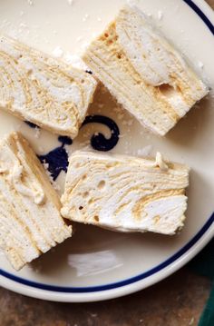 four pieces of cake sitting on top of a white plate with blue trim around it