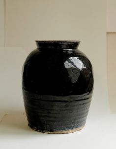 a black vase sitting on top of a white table next to a box with a piece of paper sticking out of it