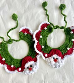 two crocheted christmas bibs with santa claus faces