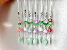 a bunch of different colored flowers hanging from a hook on a white wall next to a pink flower