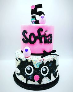 a three tiered birthday cake decorated with sprinkles and black cat faces