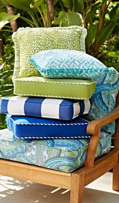 pillows stacked on top of each other on a wooden chair in front of some plants