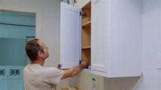 a man is working on cabinets in the kitchen with no one around him or someone else