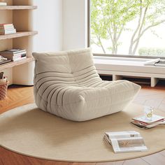 a white chair sitting on top of a wooden floor next to a book shelf filled with books