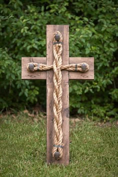 a wooden cross sitting in the grass with a rope hanging from it's center