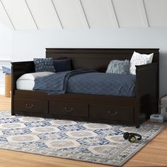 a bed sitting on top of a wooden floor next to a dresser with drawers under it