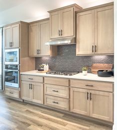 a kitchen with wooden cabinets and white counter tops, wood flooring and stainless steel appliances