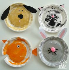 four paper plates with different animal faces on them and one is painted orange, the other white