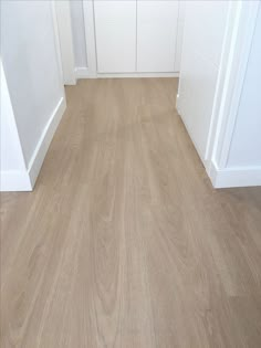 an empty room with white walls and wood floors is seen in this image from the front door