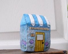 a blue and white painted rock sitting on top of a wooden table next to a potted plant