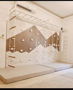 an empty room with white walls and wooden shelves on the wall are suspended by ropes