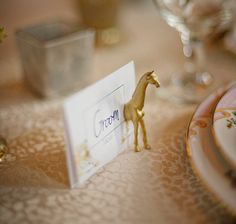 there is a small giraffe figurine sitting on the place card holder