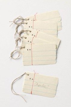 three pieces of paper with writing on them and string attached to the tags that have been pinned together