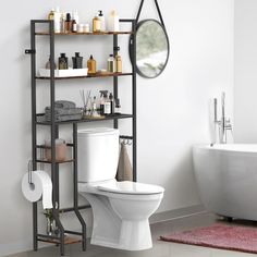 a white toilet sitting next to a bath tub in a bathroom under a round mirror