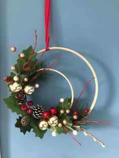 a christmas wreath hanging on the wall with pine cones and holly berry berries in it