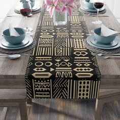 the table is set with black and gold placemats, silverware, and pink flowers