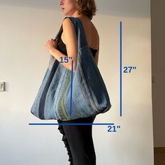 a woman carrying a large denim tote bag in front of a wall with measurements