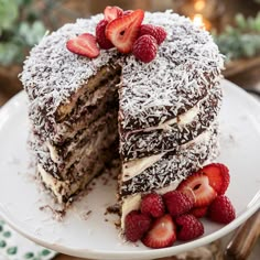 a chocolate cake with coconut and strawberries on top is cut in half to show the layers